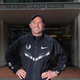 Alberto Salazar stands smiling with his hands on his hips.